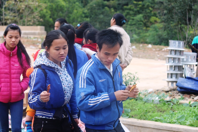 Một cặp vợ chồng người Lào đến chợ Na Mèo và thưởng thức món chân gà nướng.