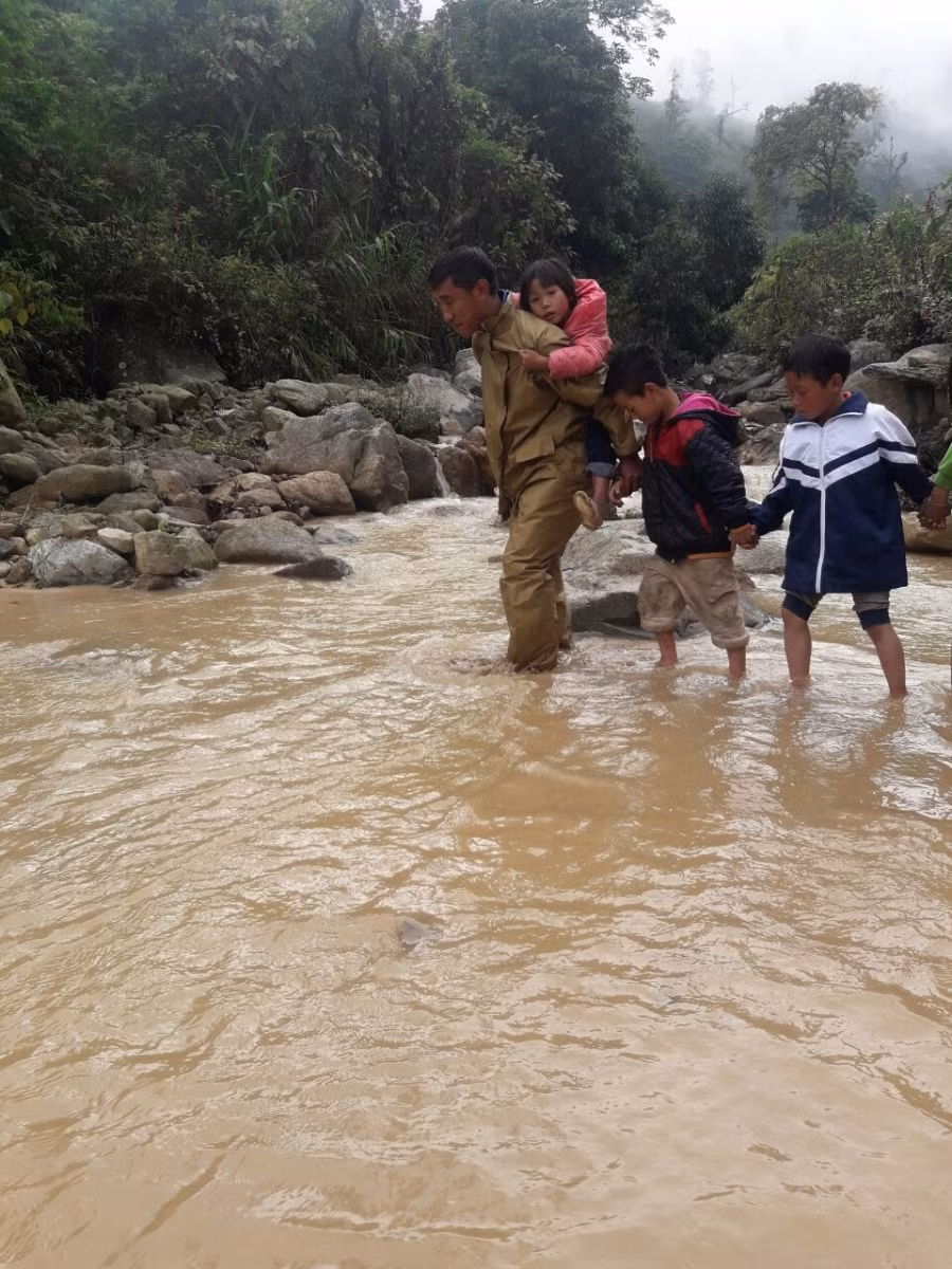 Thầy Chu Chu Cà và học sinh nắm tay nhau lội suối đến trường