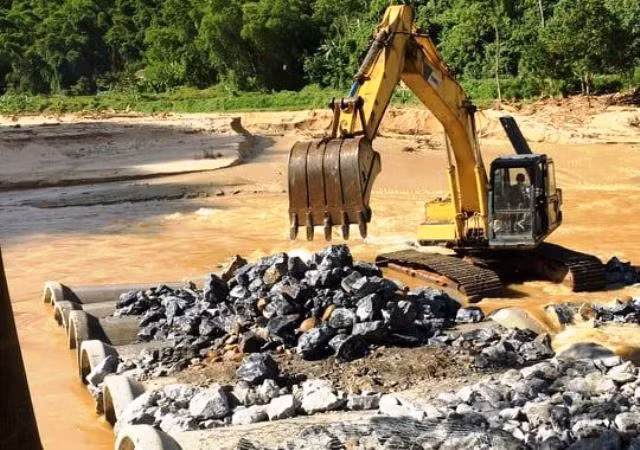 Dùng máy móc đặt hạ các ống cống ly tâm bằng bê tông xuống lòng sông.