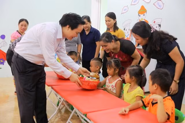 Bộ trưởng chia quà cho các cháu mẫu giáo tại Trường Mầm non Sơn Hà. Ảnh: Xuân Phú.
