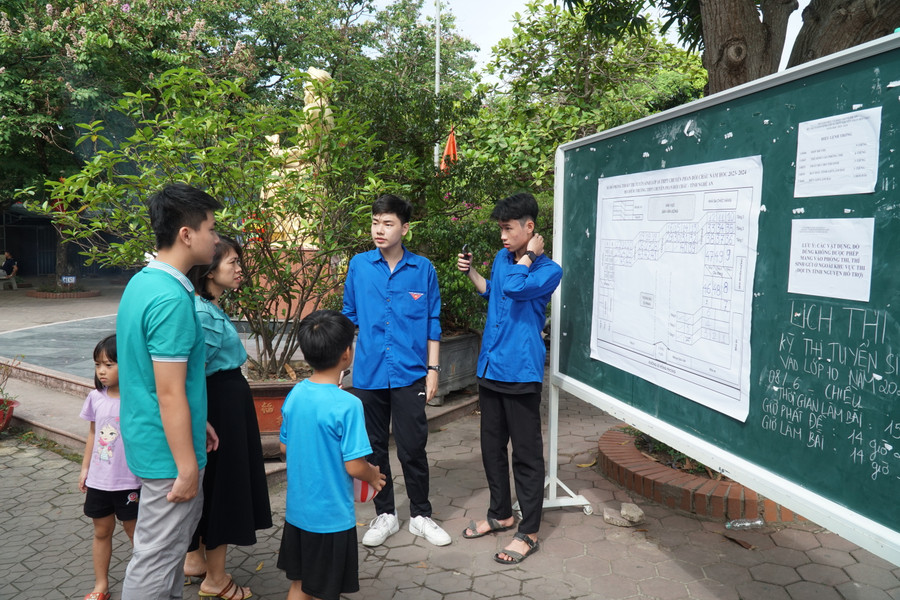 Đội tình nguyện viên hướng dẫn thí sinh và phụ huynh xác định đúng vị trí phòng thi. Ảnh: Hồ Lài.