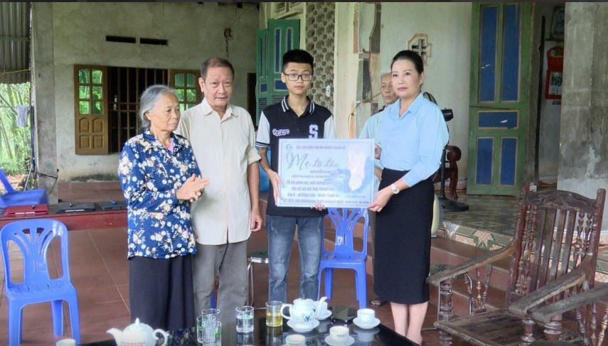 Bà Nguyễn Kim Chi - Bí thư Huyện ủy, Chủ tịch HĐND huyện Thanh Ba trao biểu trưng "Mẹ đỡ đầu" hỗ trợ cho em Mai Thanh Bình. Ảnh: Hải Minh