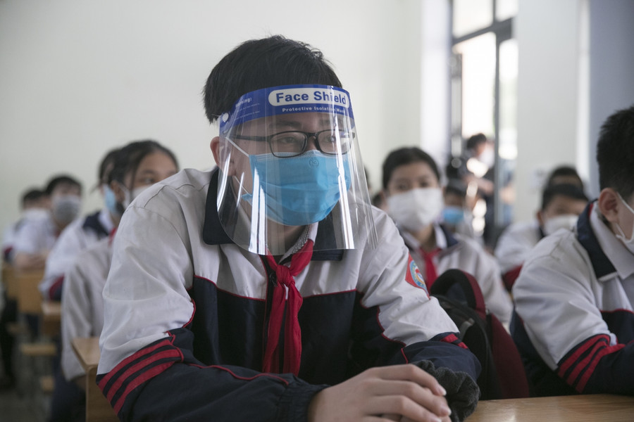 Việc cho học sinh các khối 9, 10, 11 của TP Vinh đi học trở lại được thực hiện sau khi khối 12 đến trường trực tiếp 1 tuần trước đó. Các em đến lớp thực hiện đầy đủ biện pháp phòng dịch. Một số bạn ngoài đeo khẩu trang còn đeo cả kính chống giọt bắn.