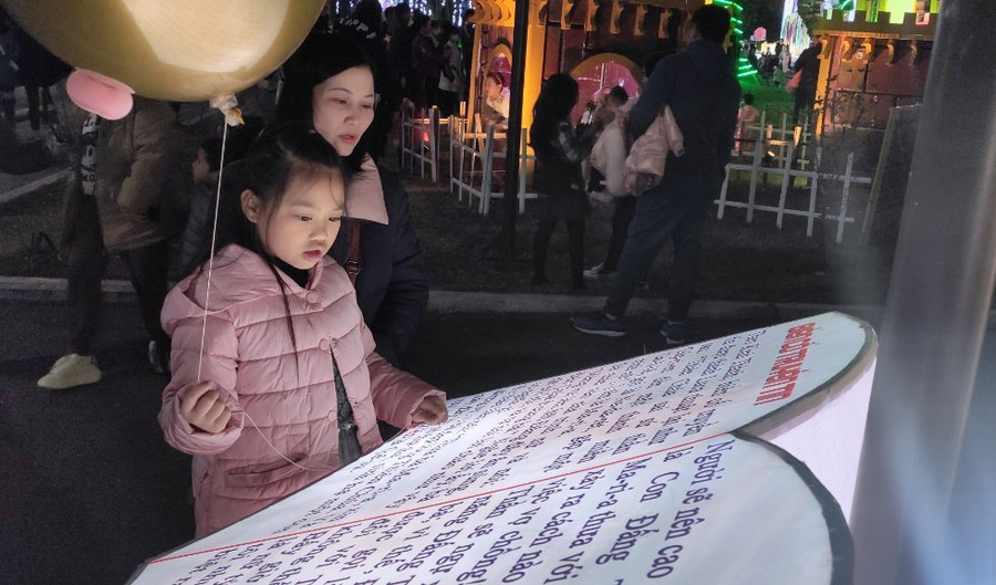 Bé gái cùng mẹ đứng xem cuốn Kinh thánh khổng lồ. Bé gái cùng mẹ đứng xem cuốn Kinh thánh khổng lồ.