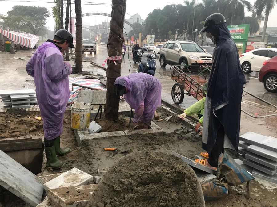 Công nhân đội mưa thi công các hạng mục trên phố đi bộ