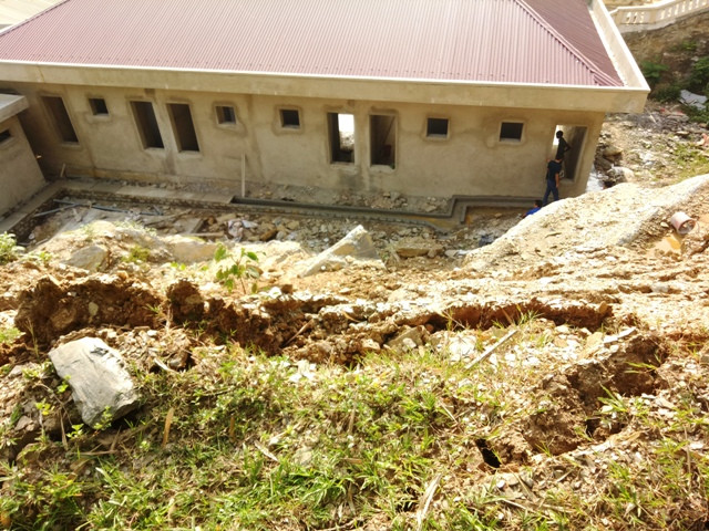 Khu nhà ở của giáo viên nhà trường đang được hoàn thiện nhưng có nguy cơ bị đất, đá từ trên cao sạt trượt xuống vùi lấp.