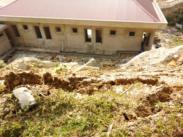 Khu nhà ở của giáo viên nhà trường đang được hoàn thiện nhưng có nguy cơ bị đất, đá từ trên cao sạt trượt xuống vùi lấp.