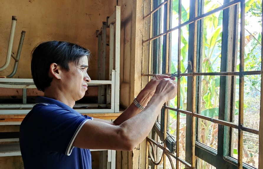 Thầy Hà Văn Chiềng đang buộc lại những thanh cửa sổ của phòng học. Ảnh: Thế Lượng. Thầy Hà Văn Chiềng đang buộc lại những thanh cửa sổ của phòng học. Ảnh: Thế Lượng.