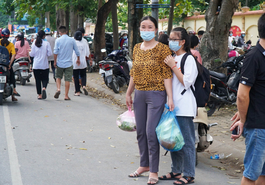 Nữ sinh được mẹ đưa từ huyện Đô Lương (cách thành phố Vinh 60km) dự thi vào trường chuyên. Cô bé vẫn còn bỡ ngỡ với thành phố, nép vai mẹ đang tay xách nách mang chờ sang đường