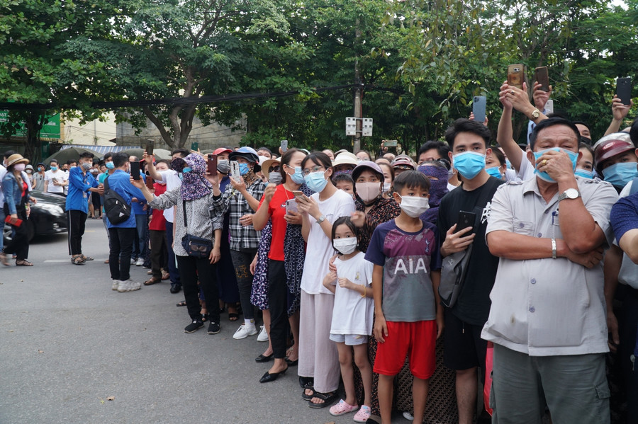 Nhiều phụ huynh cầm trên tay điện thoại, ghi lại hình ảnh con bước ra khỏi trường thi