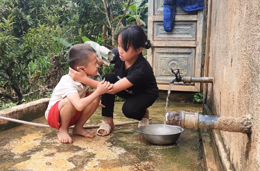 Hơ Thị Tho tranh thủ chăm sóc cậu em út.