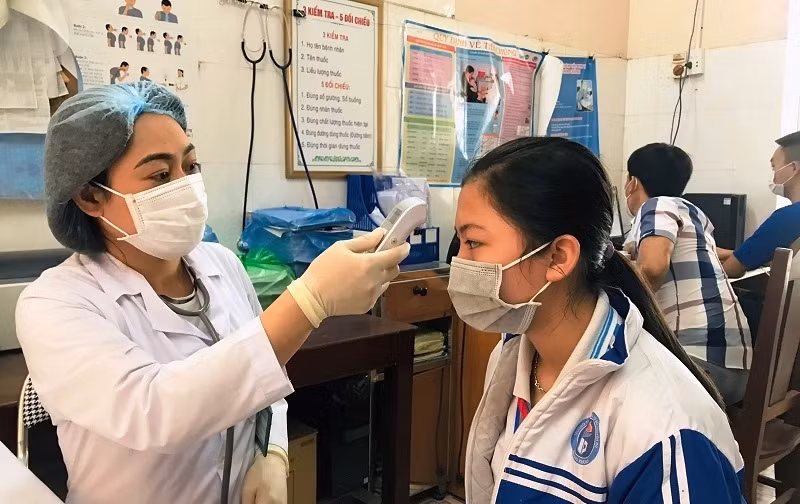 Kiểm tra thân nhiệt trước khi tiêm chủng cho các em.