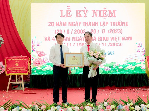 Thầy giáo Trần Xuân Chính - Hiệu trưởng trường Tiểu học Minh Tân (Bên phải) nhận Bằng khen của Bộ GD&amp;ĐT tặng nhà trường.