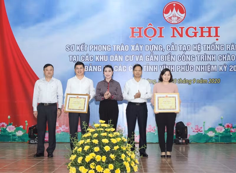 Bí thư Tỉnh ủy Vĩnh Phúc (đứng giữa) trao Bằng khen cho lãnh đạo và nhân dân huyện Vĩnh Tường và Sông Lô đã có thành tích xuất sắc trong cuộc vận động xây dựng, cải tạo cống, rãnh thoát nước, khắc phục ô nhiễm môi trường tại khu dân cư