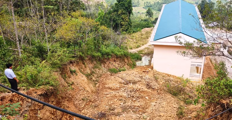 Đất ở trên núi sạt xuống thành một hào lớn xối thẳng vào vách trường.
