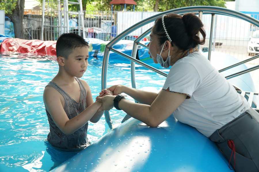 Trong mỗi buổi học, để đảm bảo an toàn, ngoài giáo viên Thể dục, còn có giáo viên chủ nhiệm và Tổng phụ trách đội tham gia quản lý, quan sát học sinh. Trong ảnh, cô Nguyễn Thị Thu Trang - GV chủ nhiệm lớp 1 Trường Tiểu học Việt - Anh động viên 1 bạn học sinh để em bình tĩnh khi ở dưới nước.