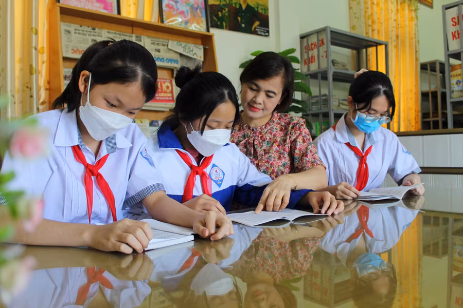 Cô Nguyễn Thị Thu Hà cùng học sinh tại thư viện của nhà trường. Hiện nay, ngoài sách giáo khoa, nhà trường còn bổ sung nhiều đầu sách pháp luật.