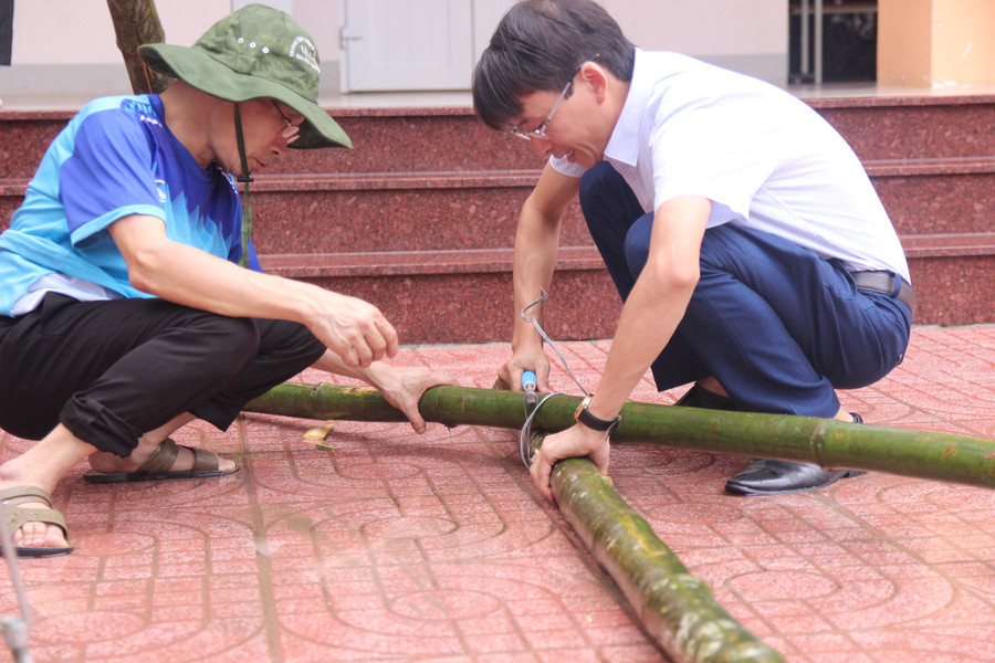 Dùng dây thép và kìm buộc các cây mét lại với nhau làm vật chống đỡ cho cây xanh
