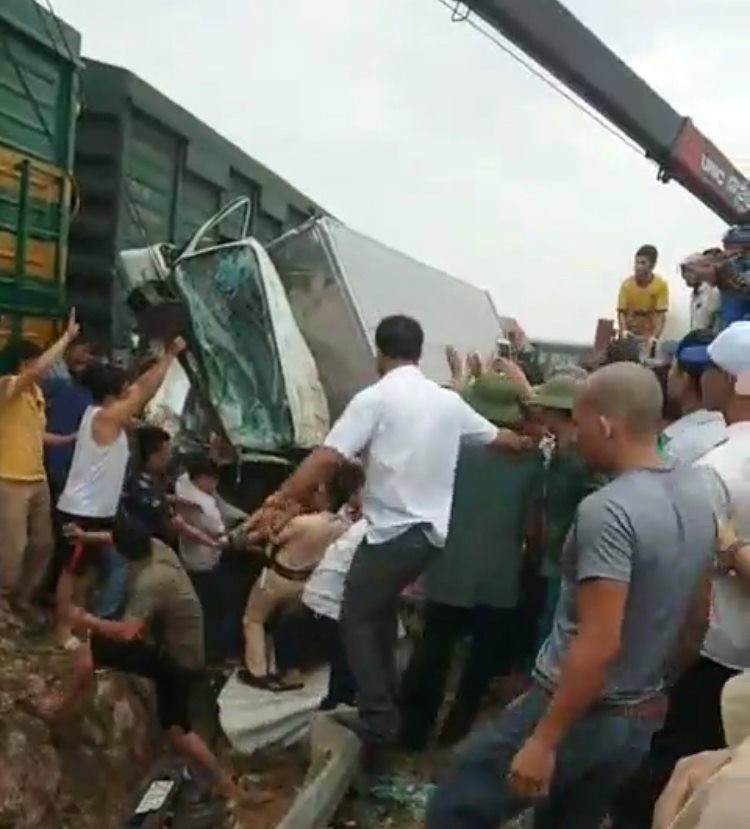 Người dân hỗ trợ lực lượng chức năng đưa tài xế xe tải mắc kẹt trong cabin ra ngoài