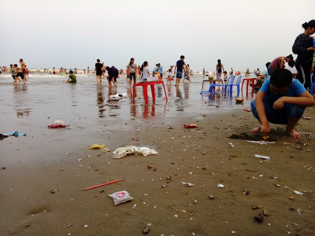 Trẻ em ngôi chơi bên mép biển đầy rác thải