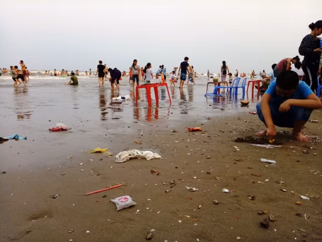 Trẻ em ngôi chơi bên mép biển đầy rác thải