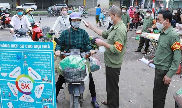 Kiểm tra thân nhiệt cho người cung cấp hàng hóa tại chợ đầu mối Minh Khai (quận Bắc Từ Liêm)