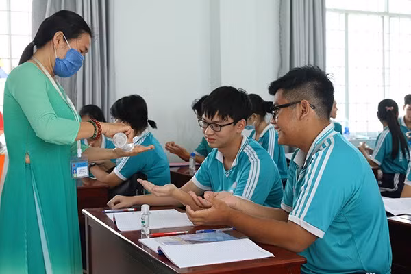 Học sinh ở Kiên Giang được giáo viên hướng dẫn sử dụng dung dịch sát khuẩn đúng cách để phòng dịch Covid-19. Ảnh: ITN
