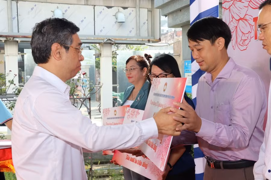 Phó Bí thư Thành ủy TPHCM Nguyễn Phước Lộc trao bảng tượng trưng hỗ trợ chăm lo người nghèo cho quận, huyện. (Ảnh: Ủy ban Mặt trận Tổ quốc TPHCM)