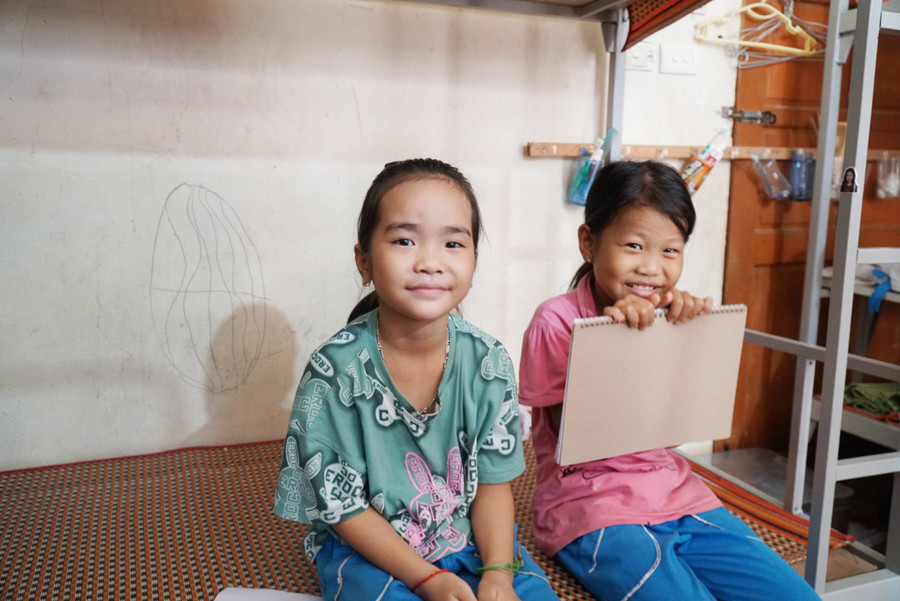 Em Lương Thị Yến Nhi (bên trái) lên lớp 3 và cũng là năm đầu tiên từ bản Canh về trường chính học bán trú. &quot;Mấy ngày đầu ở bán trú tại trường nhớ nhà nên em có khóc. Nhưng bây giờ quen rồi, có các bạn ở cùng và thầy cô nên vui hơn&quot;, Yến Nhi nói. Ảnh: Hồ Lài.