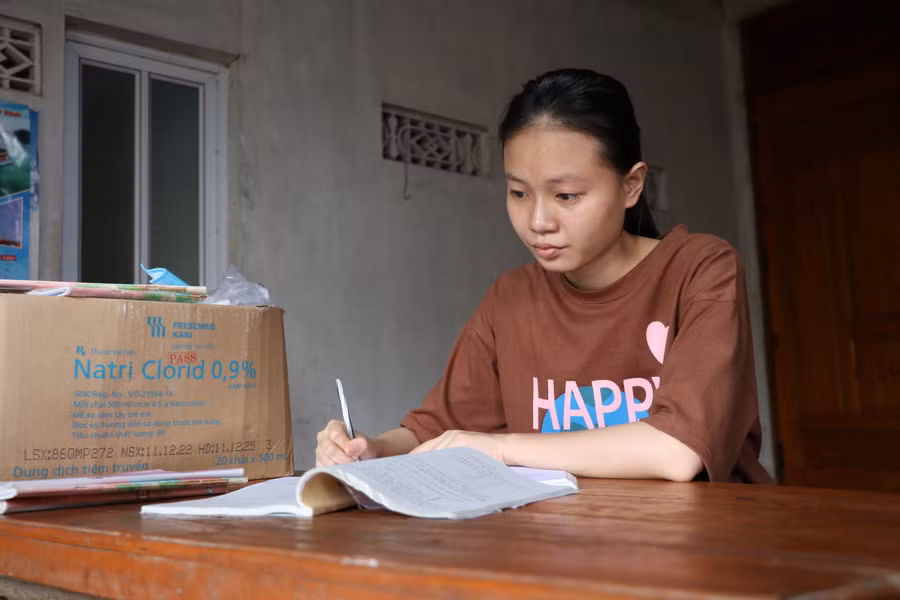 Nén nỗi đau mất bố mẹ, nữ sinh lớp 12 tranh thủ thời gian đọc lại sách vở trức khi thi tốt nghiệp THPT. Ảnh: Hồ Lài.