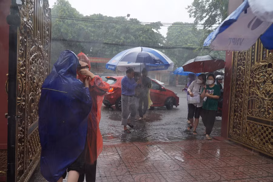 Buổi thi môn Toán, tại TP Vinh, trời bất ngờ đổ mưa to như trút nước. Nhiều thí sinh xắn quần, được bố mẹ che ô và tình nguyện viên đón đưa vào trong điểm thi.