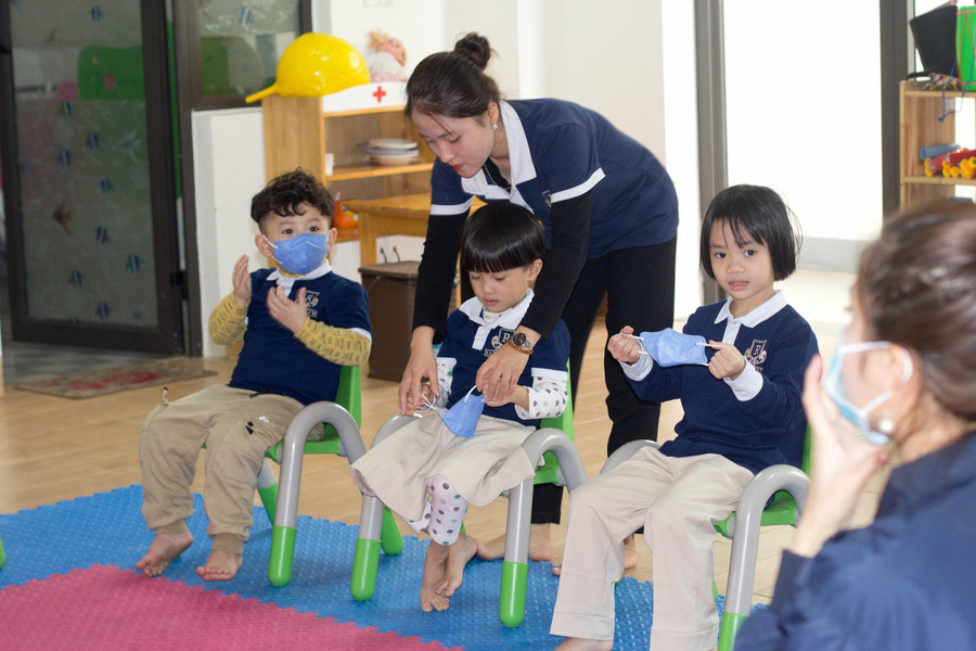 Cô giáo Trường Mầm non Rainbow đeo khẩu trang cho các bé