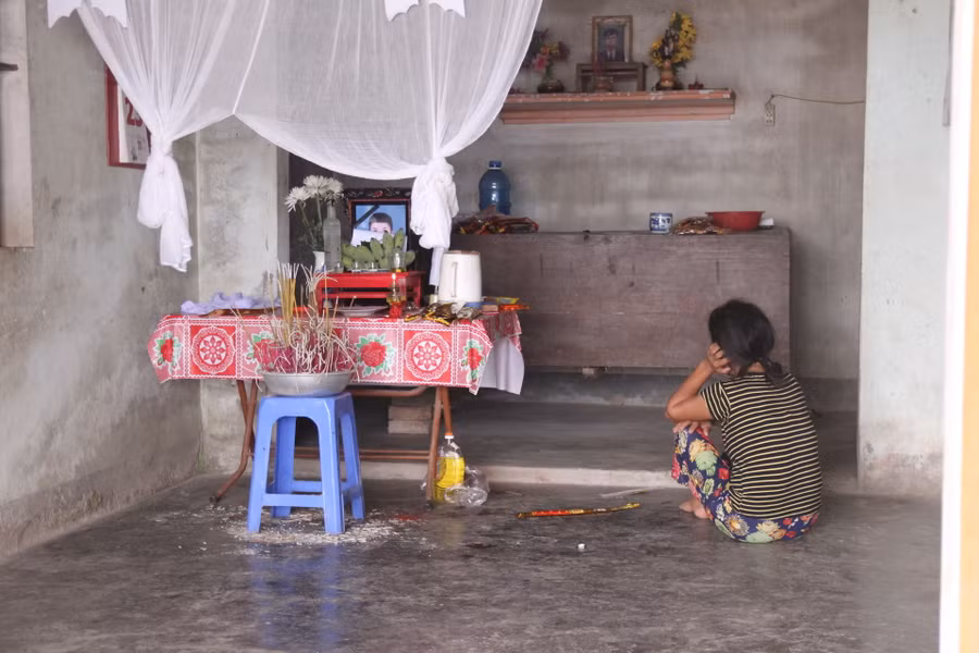 Người mẹ nghèo ngồi bất động trước di ảnh con là em Nguyễn Gia Tiến (HS Trường THPT Nguyễn Cảnh Chân).