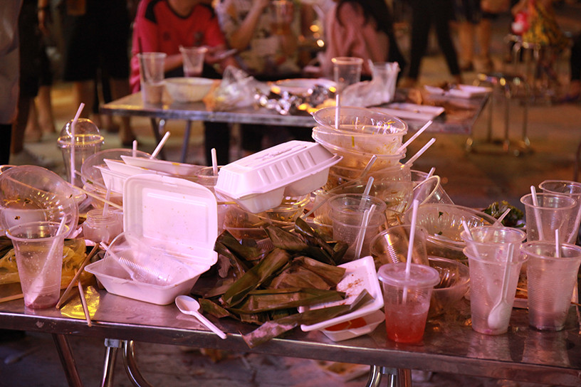 Hộp nhựa, cốc, thìa nhựa, vỏ bánh xếp chồng lên nhau mà không có thùng rác để chứa.