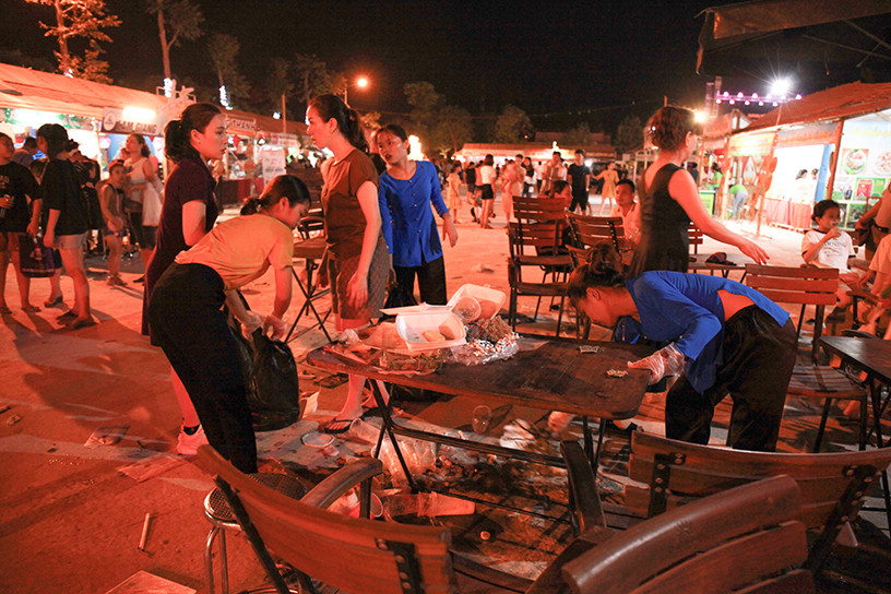 Nhân viên dọn dẹp rác thải do người dân bỏ lại khi đêm khai mạc kết thúc.