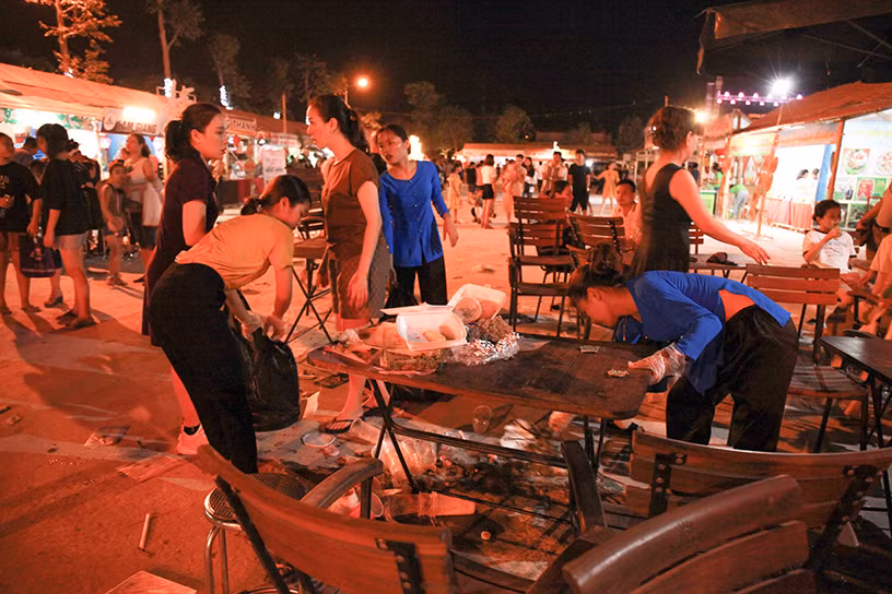 Nhân viên dọn dẹp rác thải do người dân bỏ lại khi đêm khai mạc kết thúc.