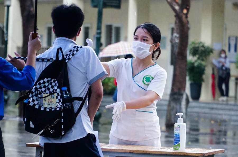 Tình nguyện viên che mưa cho thí sinh thi vào lớp 10 Hà Nội.