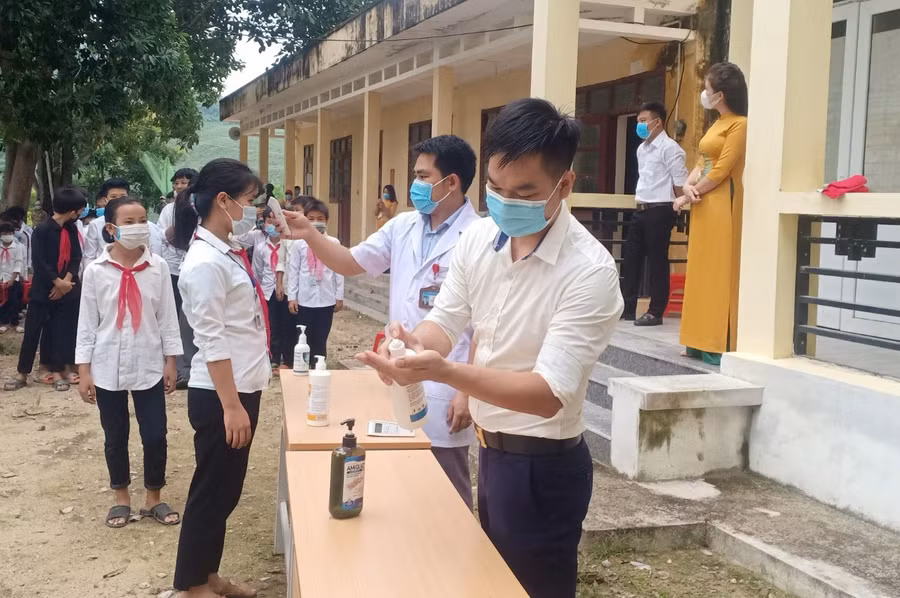 Kiểm tra thân nhiệt và sát khuẩn tay cho học sinh.