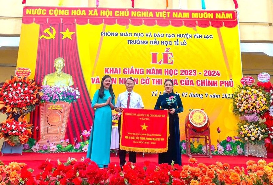 Bà Nguyễn Thị Huấn - Phó Bí thư Thường trực Huyện ủy huyện Yên Lạc (thứ nhất bên phải) trao Cờ thi đua của Chính phủ tặng Trường Tiểu học Tề Lỗ đơn vị xuất sắc trong phong trào thi đua năm học 2021 - 2022.
