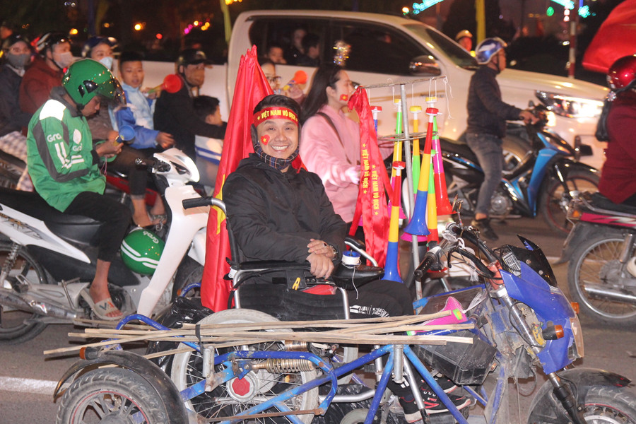 Một người khuyết tật cũng ra đường bán cờ, băng rôn, kèn và cùng hòa vào dòng người ăn mừng chiến thắng