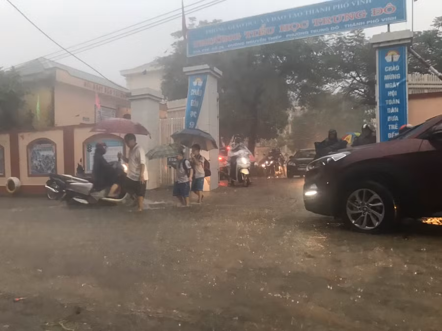 Các em học sinh Trường Tiểu học Trung Đô (TP Vinh, Nghệ An) tan trường muộn vì chờ bố mẹ vượt đường ngập lụt đến đón.