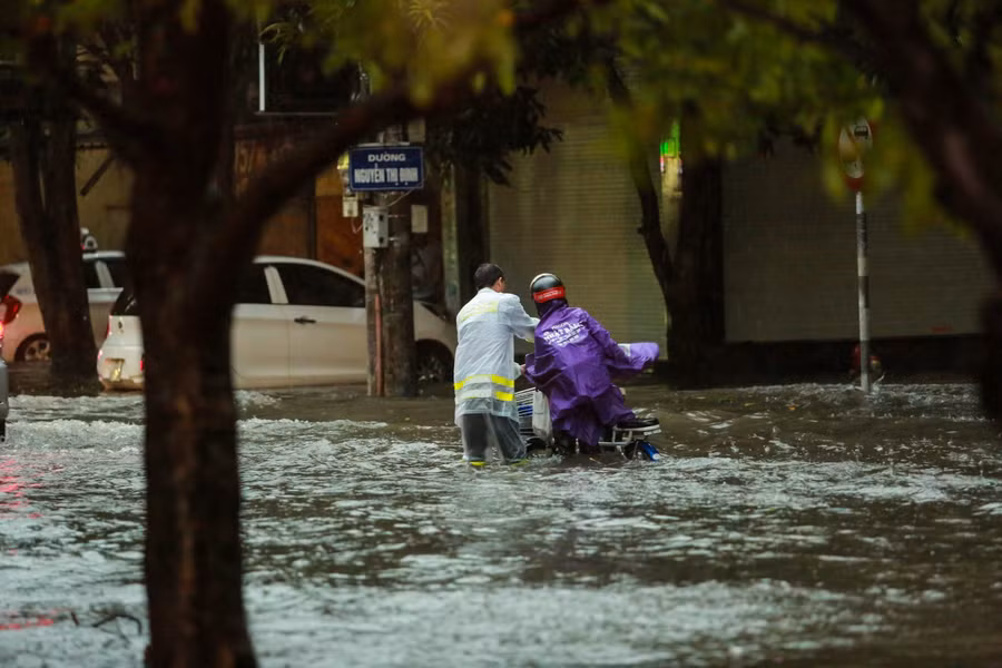 Cảnh sát giao thông giúp đỡ một người dân vượt qua đoạn ngập nước khi qua đường Nguyễn Thị Định