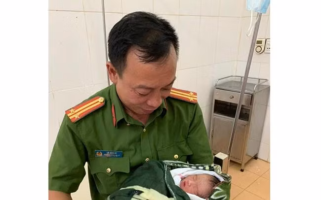 Trung tá Lò Văn Ức đang bế cháu bé tại Bệnh viện Đa khoa huyện Thuận Châu