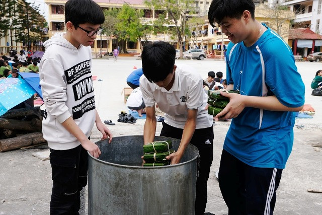 Các bạn nam xếp bánh vào nồi để nấu