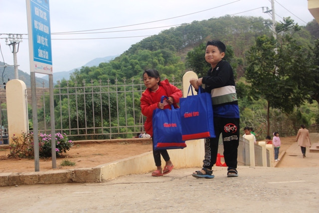 Hai em học sinh Trường Tiểu học và THCS thị trấn Mường Lát khệ nệ với túi quà Tết của mình vừa nhận.