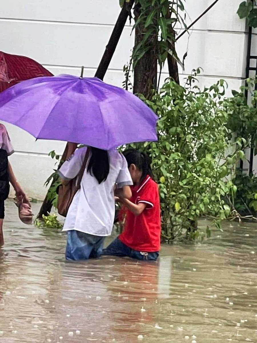 Hai nữ học sinh ở TP Thanh Hóa dắt nhau đến trường trong mưa lớn. (Ảnh: Bạn đọc cung cấp)