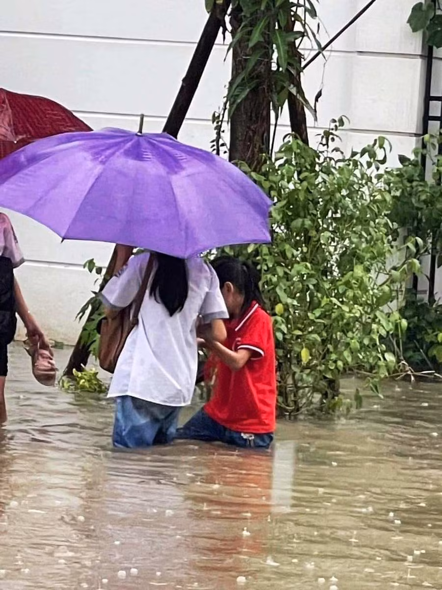 Hai nữ học sinh ở TP Thanh Hóa dắt nhau đến trường trong mưa lớn. (Ảnh: Bạn đọc cung cấp)