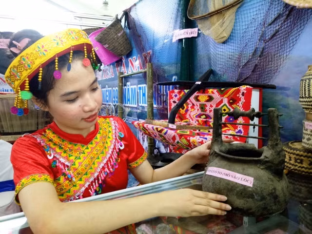 Thiếu nữ dân tộc giới thiệu cổ vật tại triển lãm.
