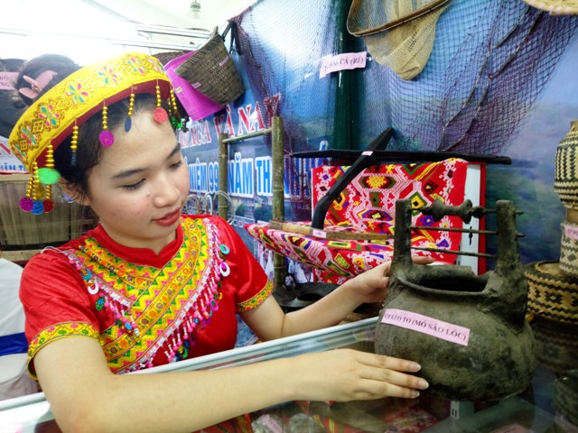 Thiếu nữ dân tộc giới thiệu cổ vật tại triển lãm.