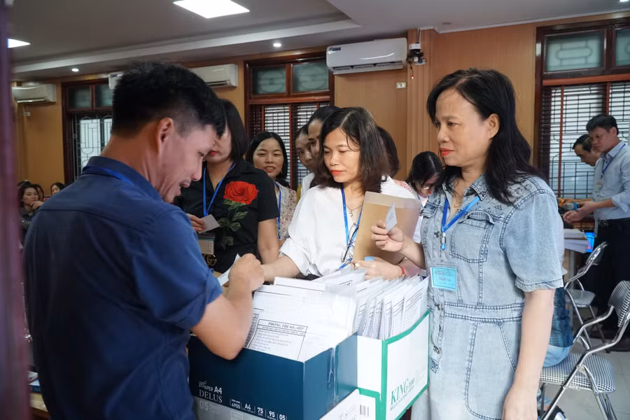 Giám thị bốc thăm phòng coi thi và nhận túi đựng phiếu làm bài của thí sinh. Ảnh: Hồ Lài.